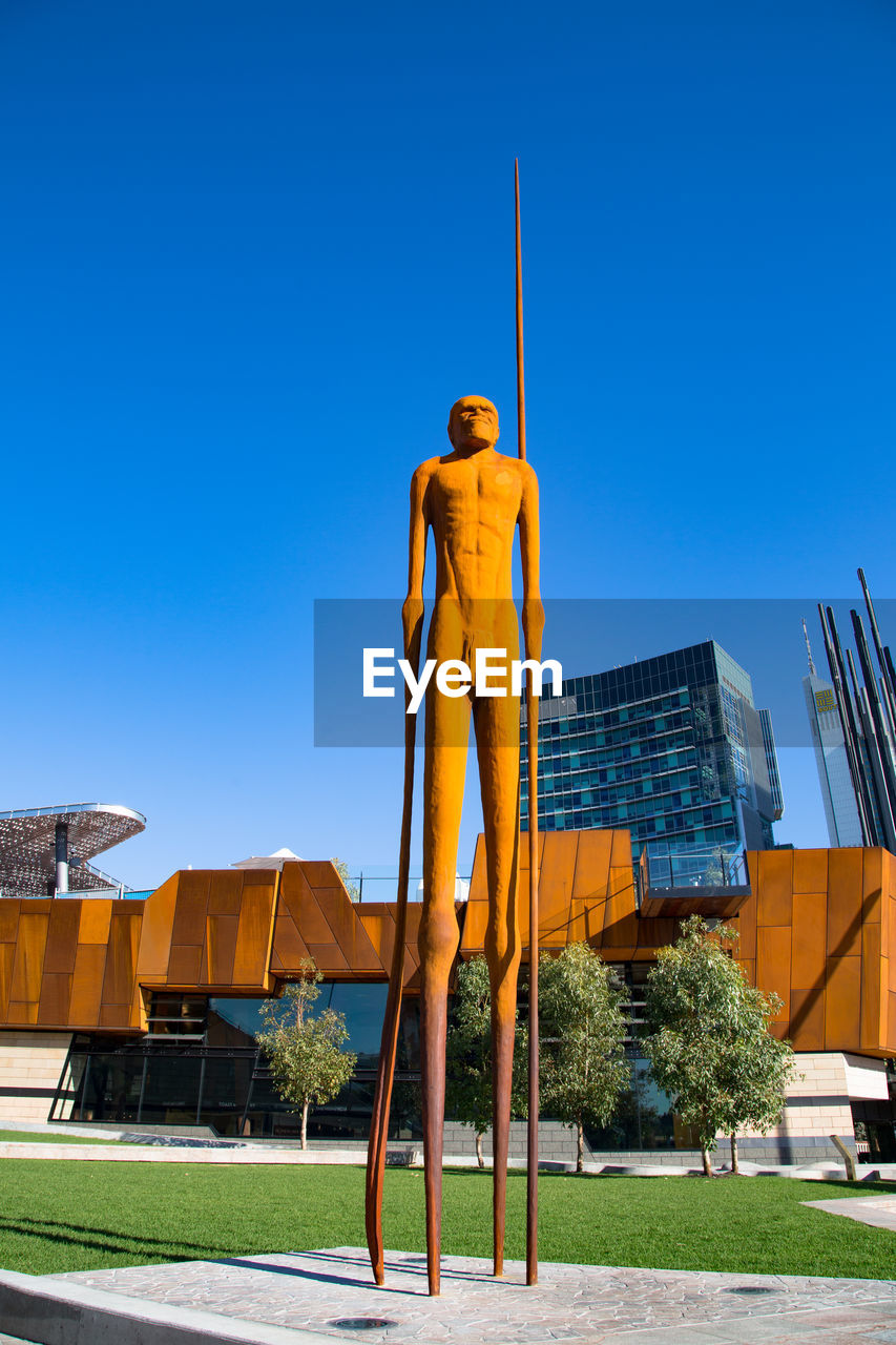 LOW ANGLE VIEW OF STATUE AGAINST BUILT STRUCTURE