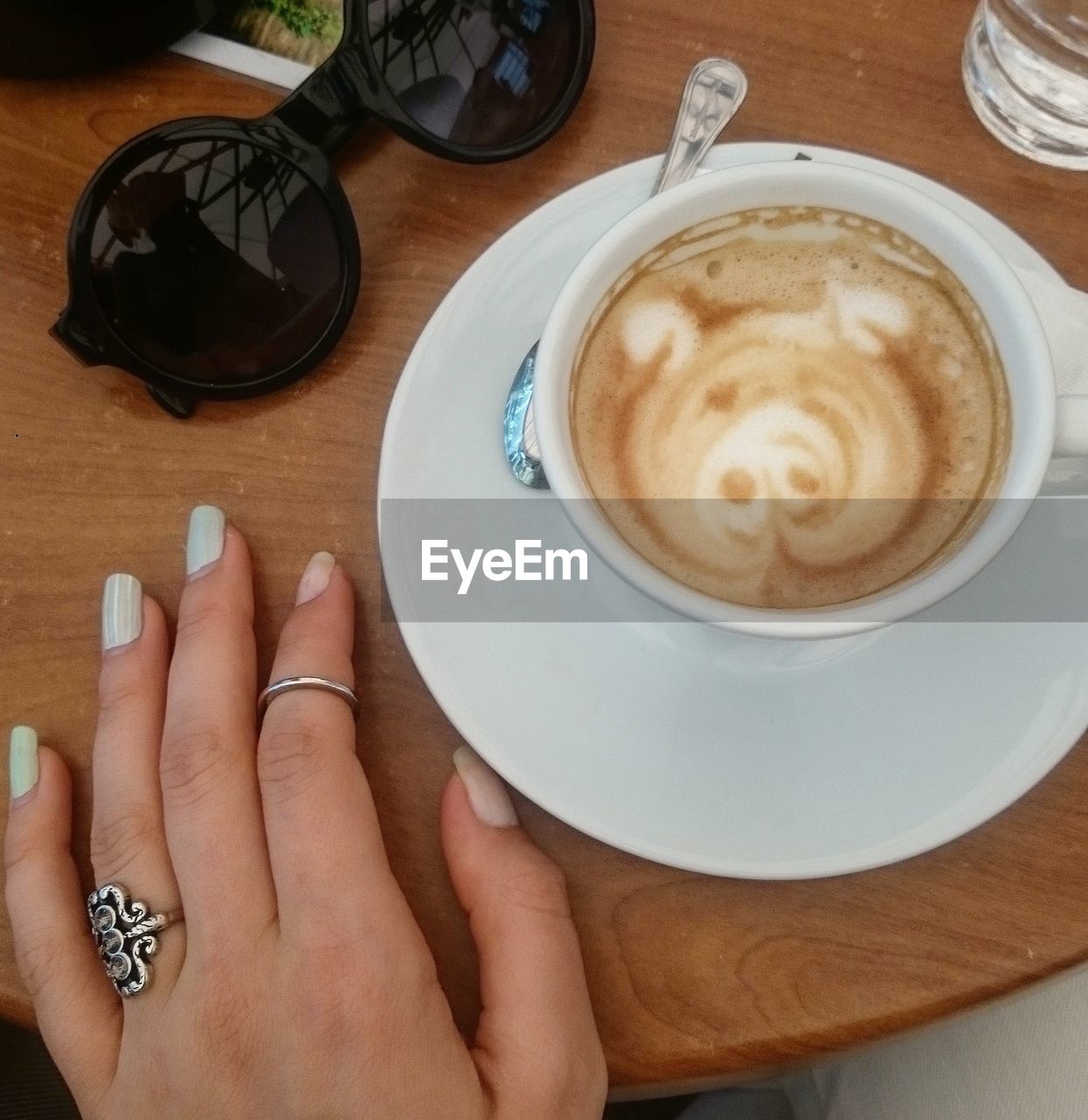 Cropped hand by coffee on table at restaurant