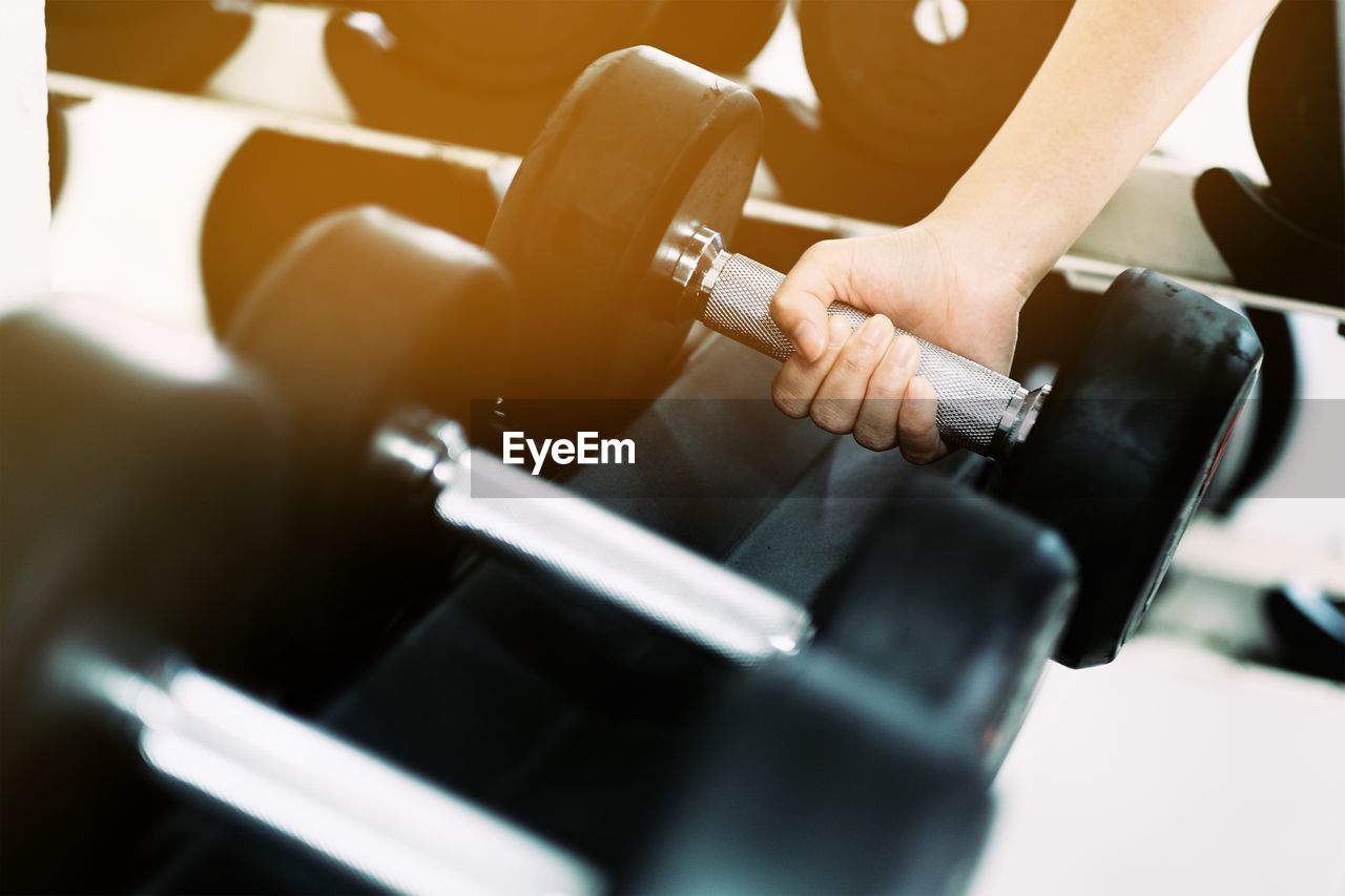 Cropped hand holding dumbbell at gym