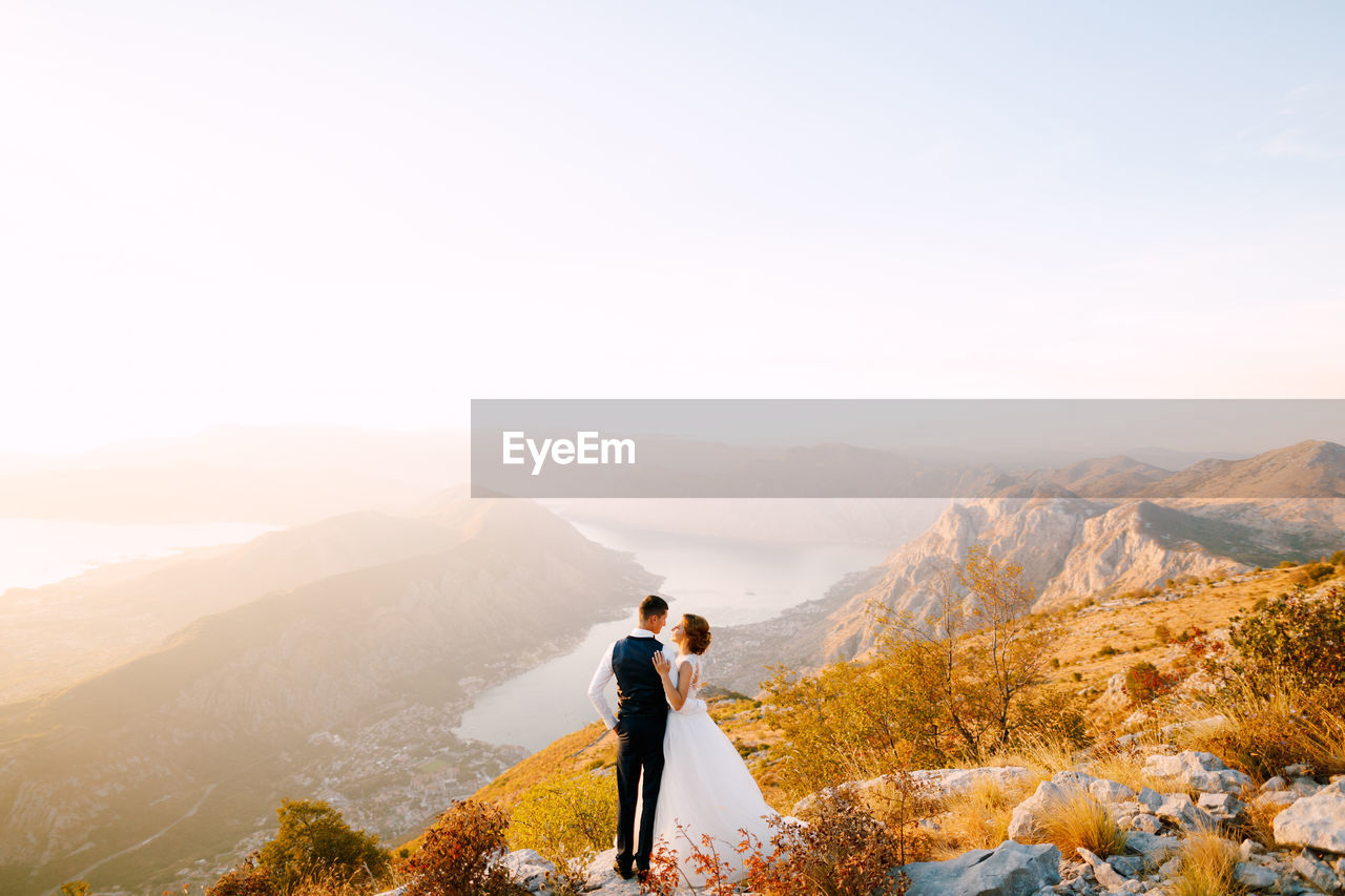 MEN STANDING ON MOUNTAIN AGAINST SKY