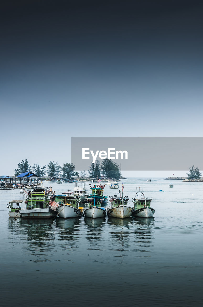 Boats moored on river against clear sky