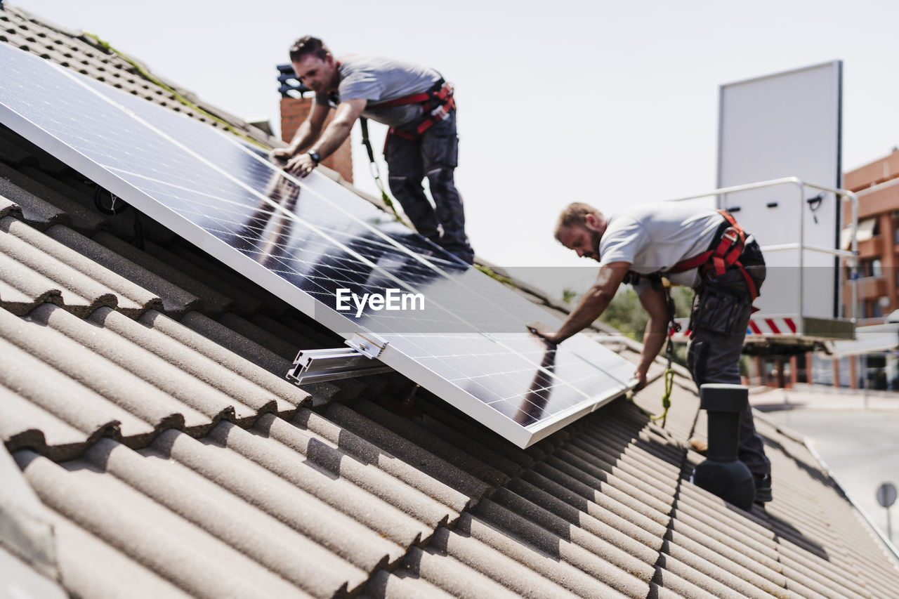 Technicians installing solar panels on rooftop