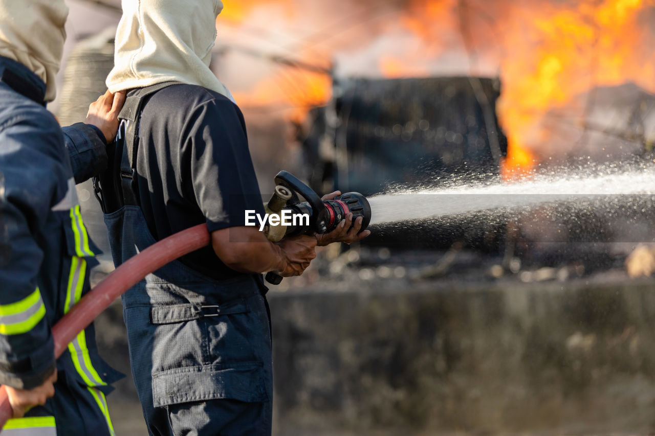 Fireman or firefighter spraying water from big water hose to prevent fire