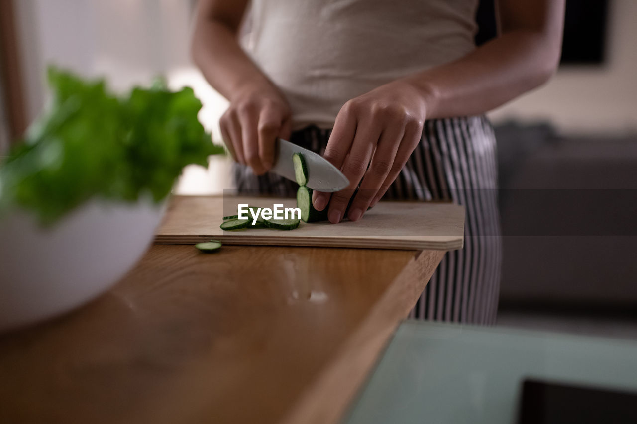 Cropped african american female slicing cucumber