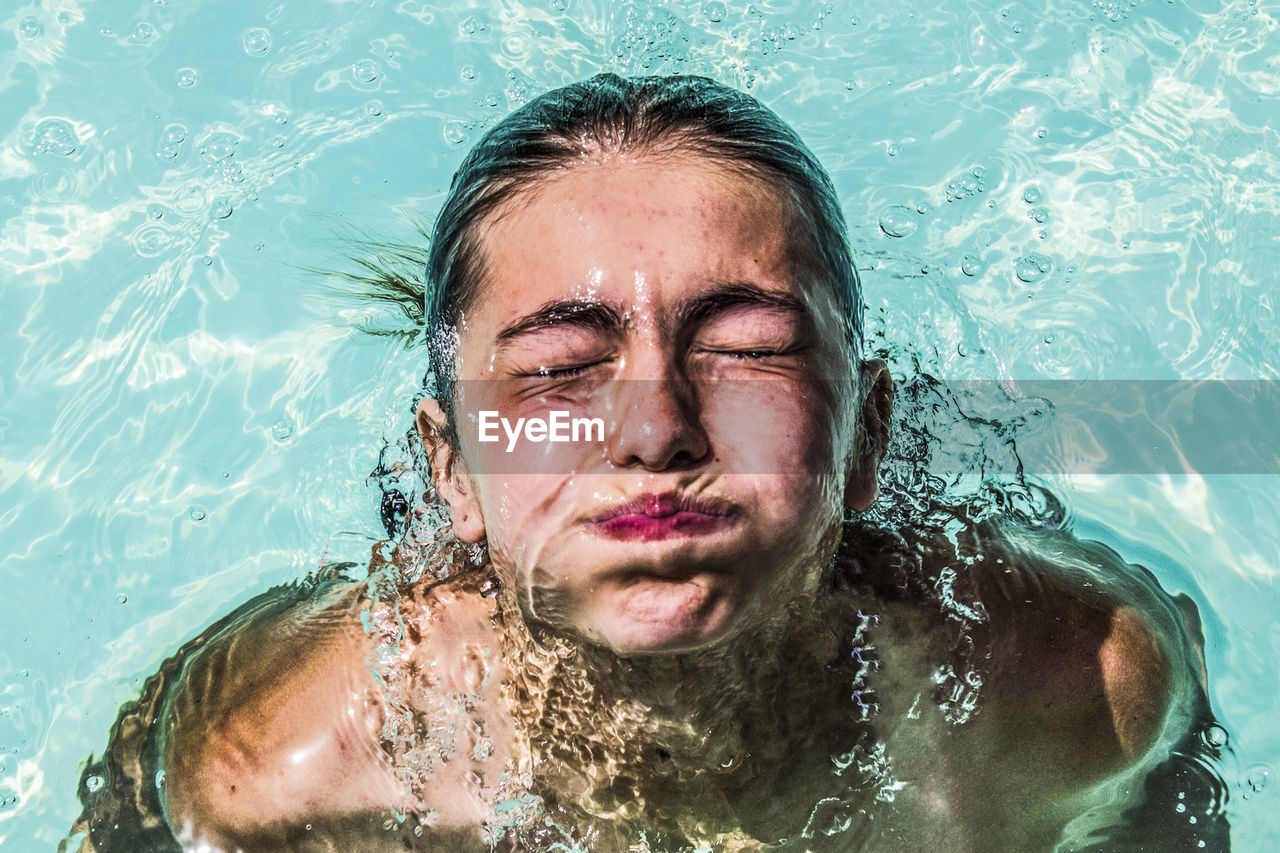 PORTRAIT OF WOMAN SWIMMING IN POOL