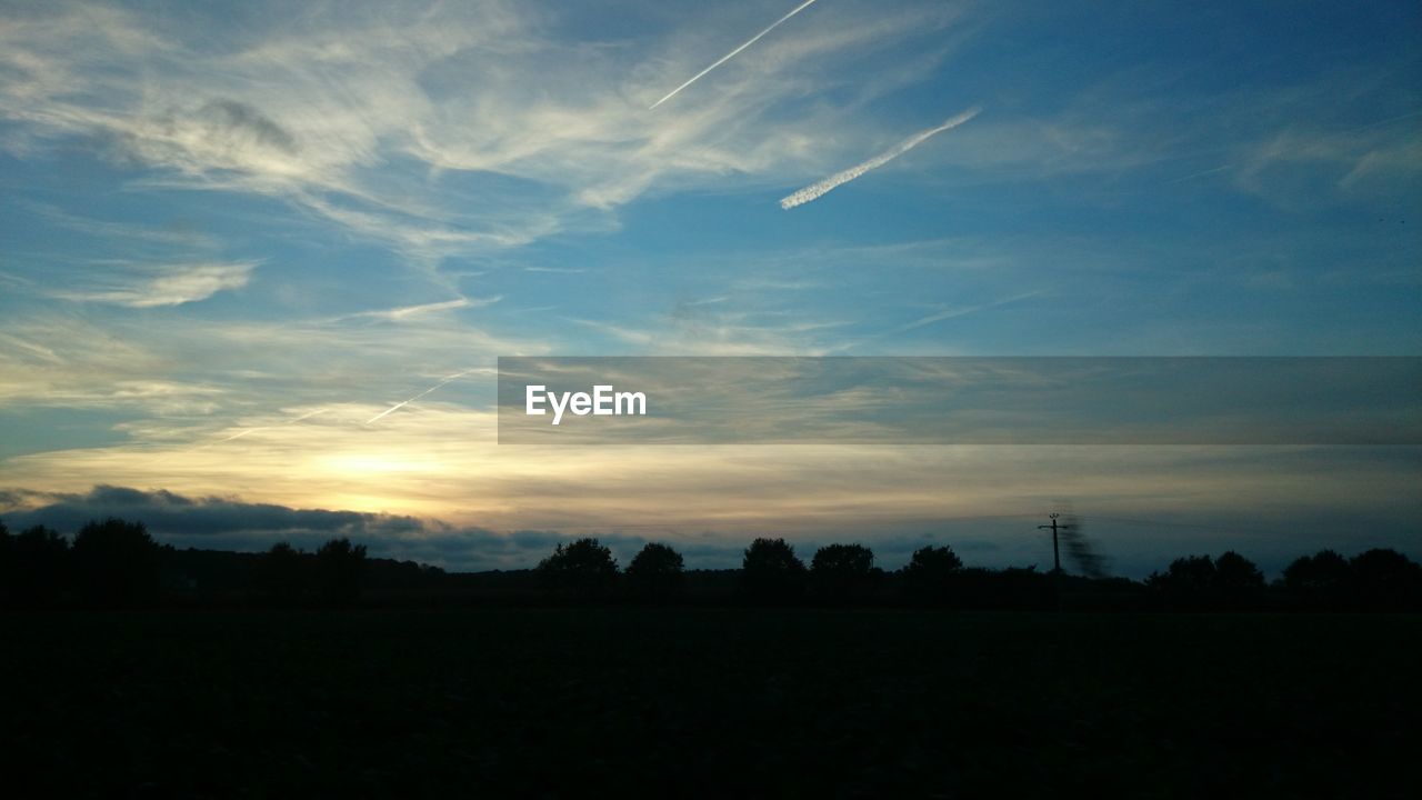 Silhouette landscape against cloudy sky during sunset