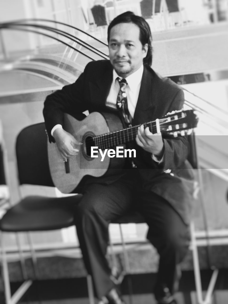 Portrait of man playing guitar while sitting on chair