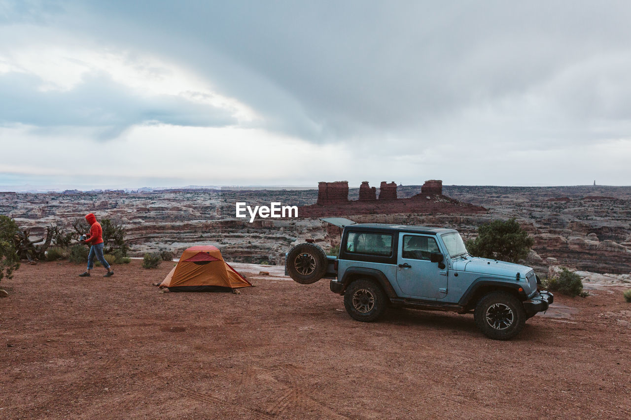 Jeep parked next to an orange tent on a rainy day in canyonlands utah