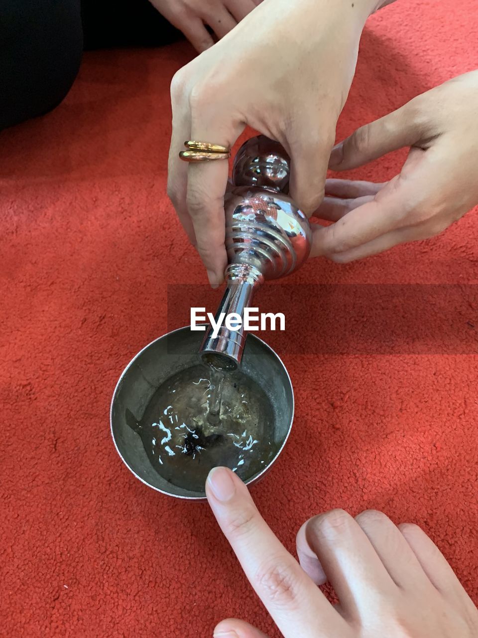 HIGH ANGLE VIEW OF WOMAN HAND HOLDING CUP OF RED POURING