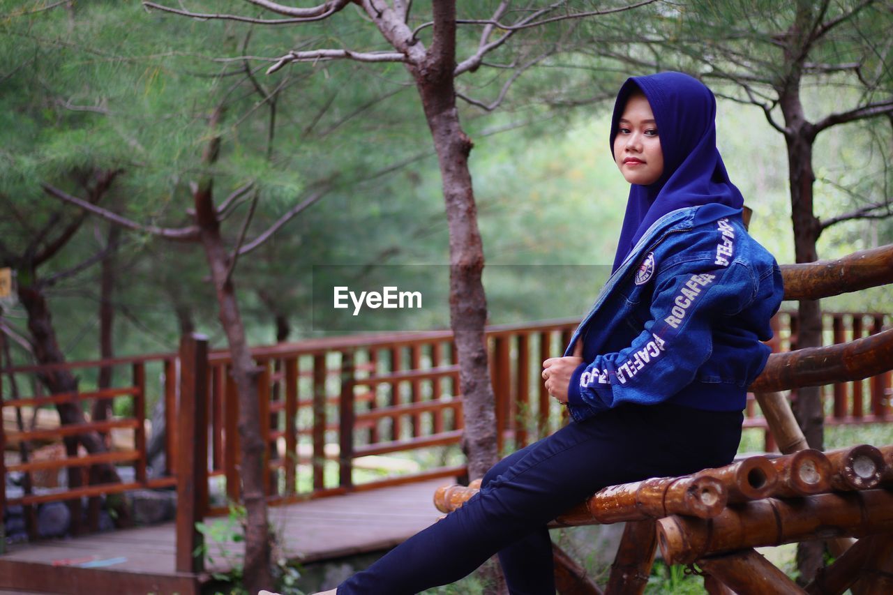 Full length of woman standing by tree in forest