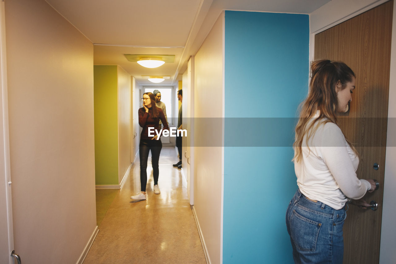 Side view of woman unlocking door standing in college dorm