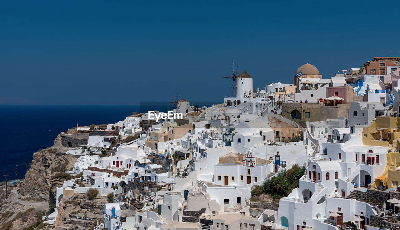 High angle view of buildings in city against blue sky