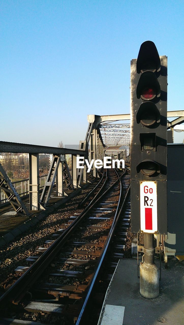 Close-up of railway signal against tracks and clear sky