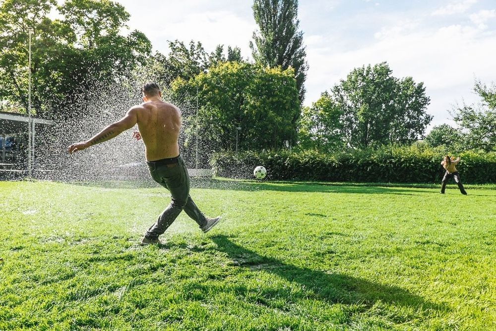 REAR VIEW OF MAN PLAYING ON GRASSY FIELD