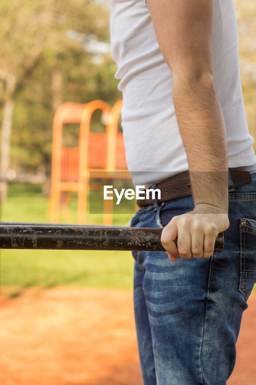 Midsection of man exercising on monkey bars