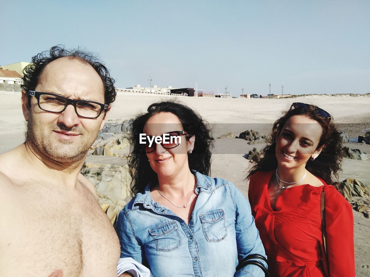 Portrait of family standing at beach against sky