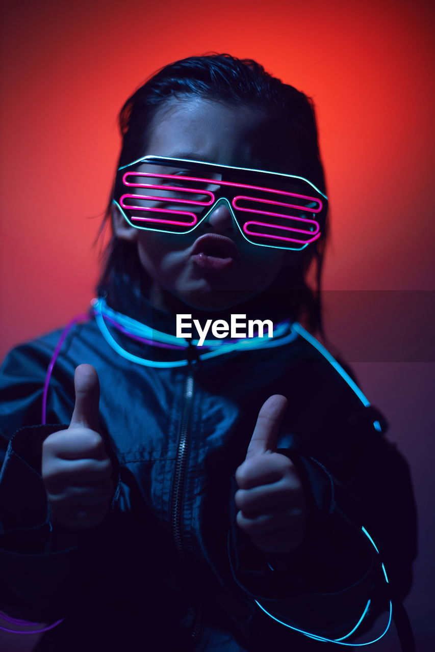 Portrait of a boy child from the future in neon glasses and jacket at night