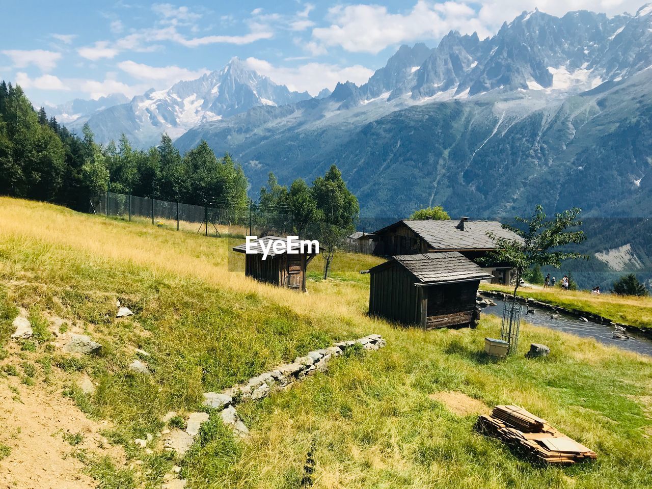 House on field by mountains against sky