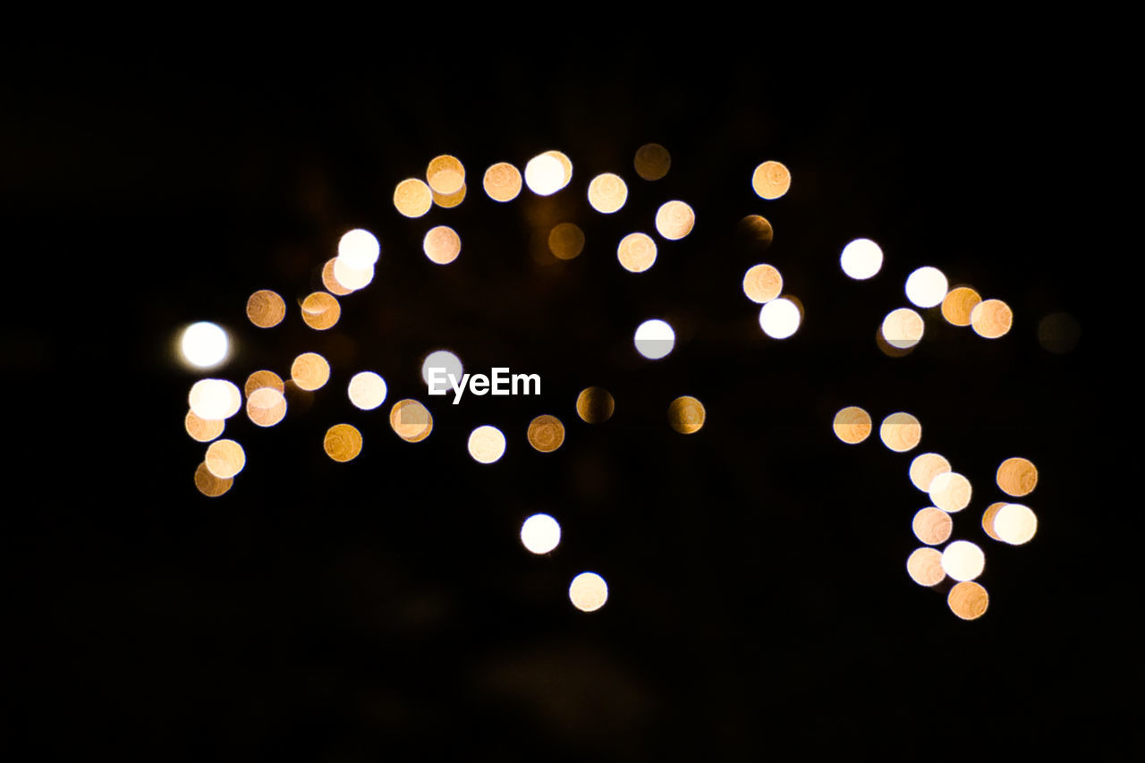 DEFOCUSED IMAGE OF ILLUMINATED LIGHTS AGAINST SKY