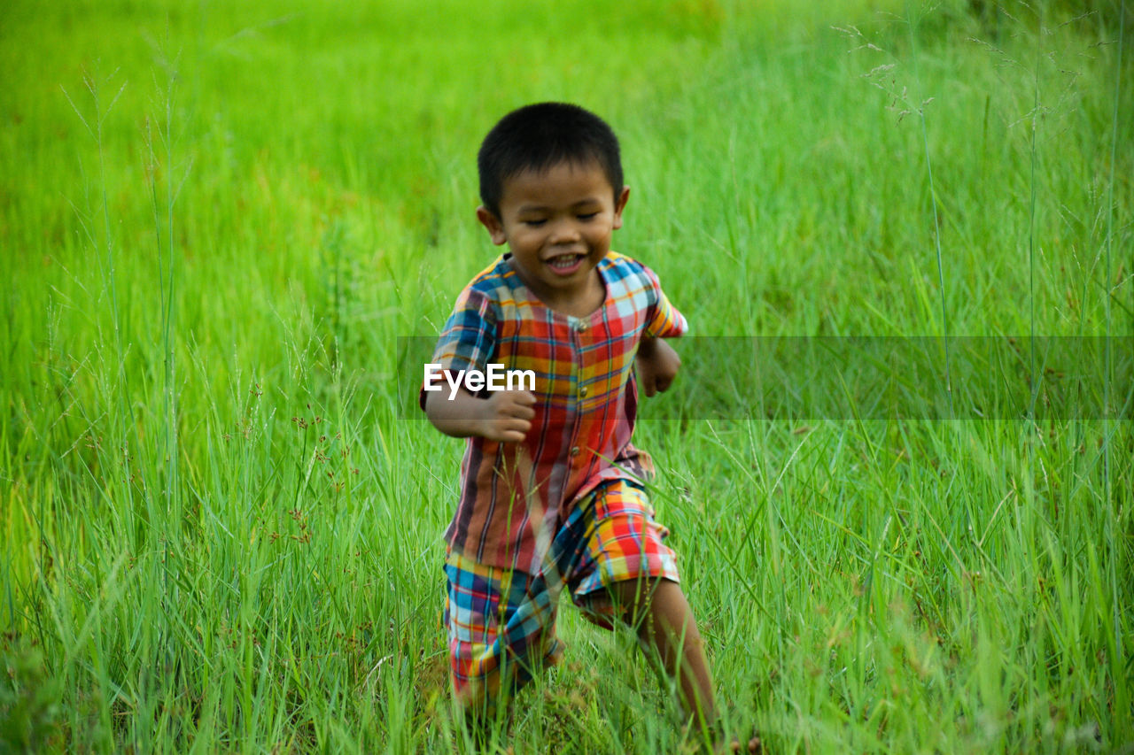 FULL LENGTH OF A BOY SMILING ON FIELD