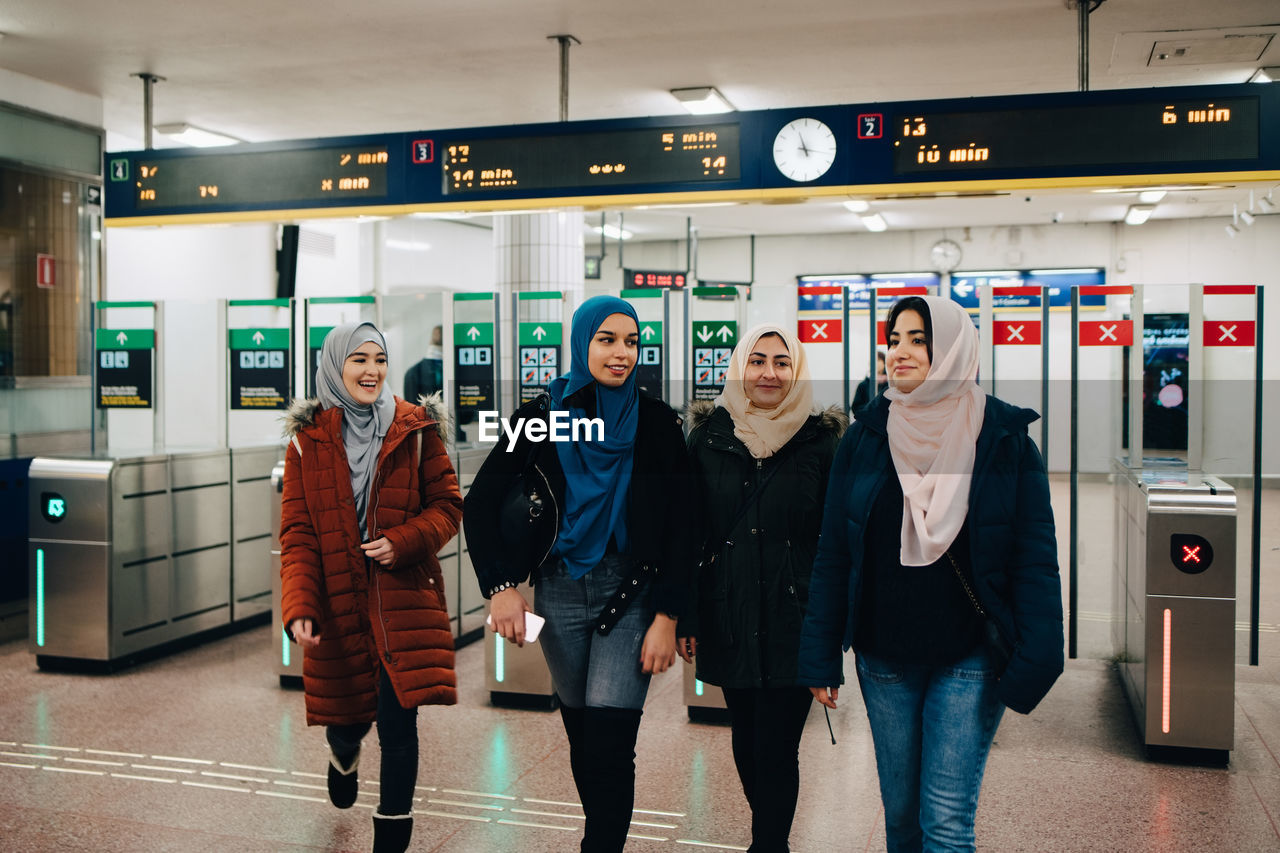 Happy multi-ethnic muslim friends walking at subway station