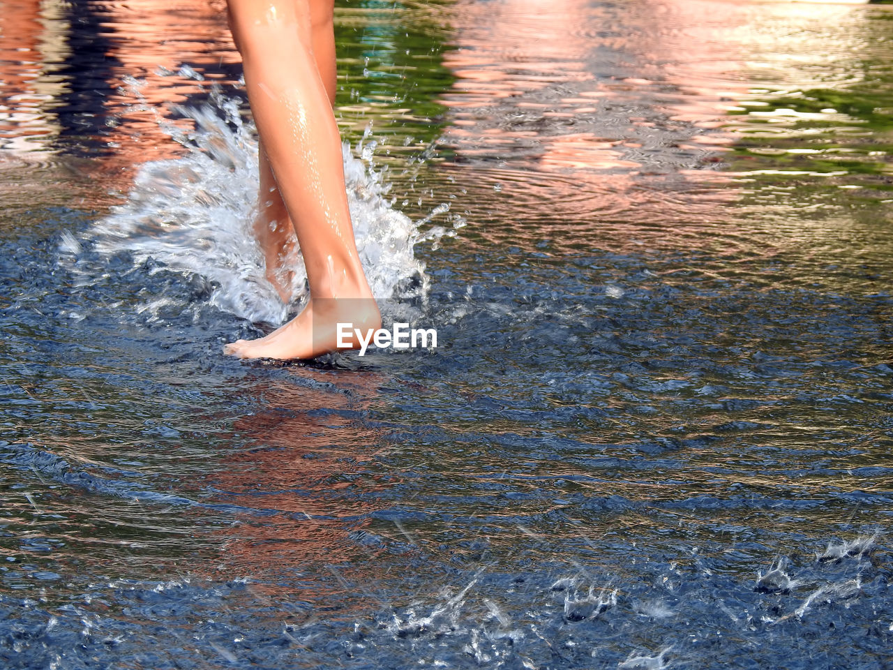 Low section of woman splashing water