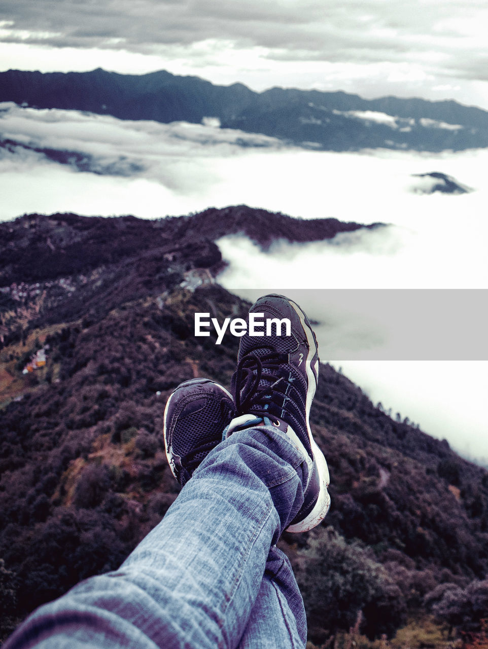 Low section of person on cliff amidst cloud