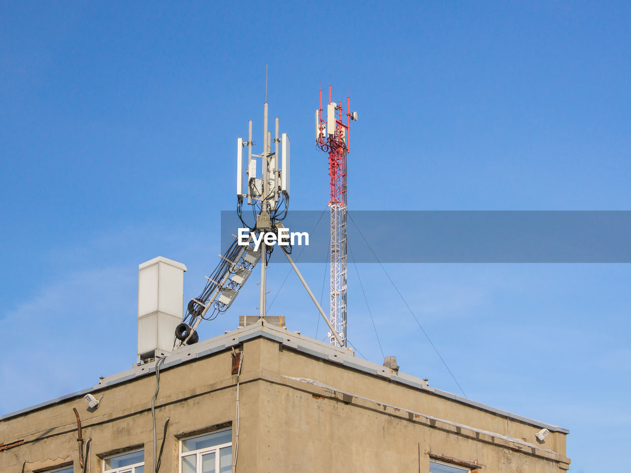 LOW ANGLE VIEW OF CRANE BY BUILDING AGAINST SKY