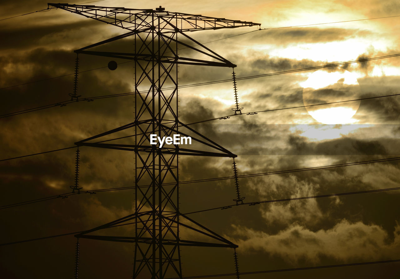 Low angle view of silhouette electricity pylon against sky