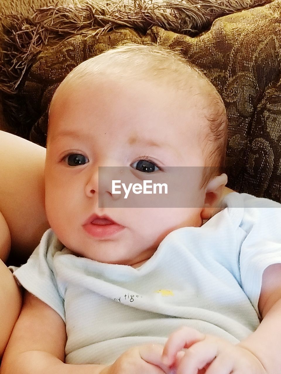 PORTRAIT OF CUTE BABY GIRL LYING ON SOFA