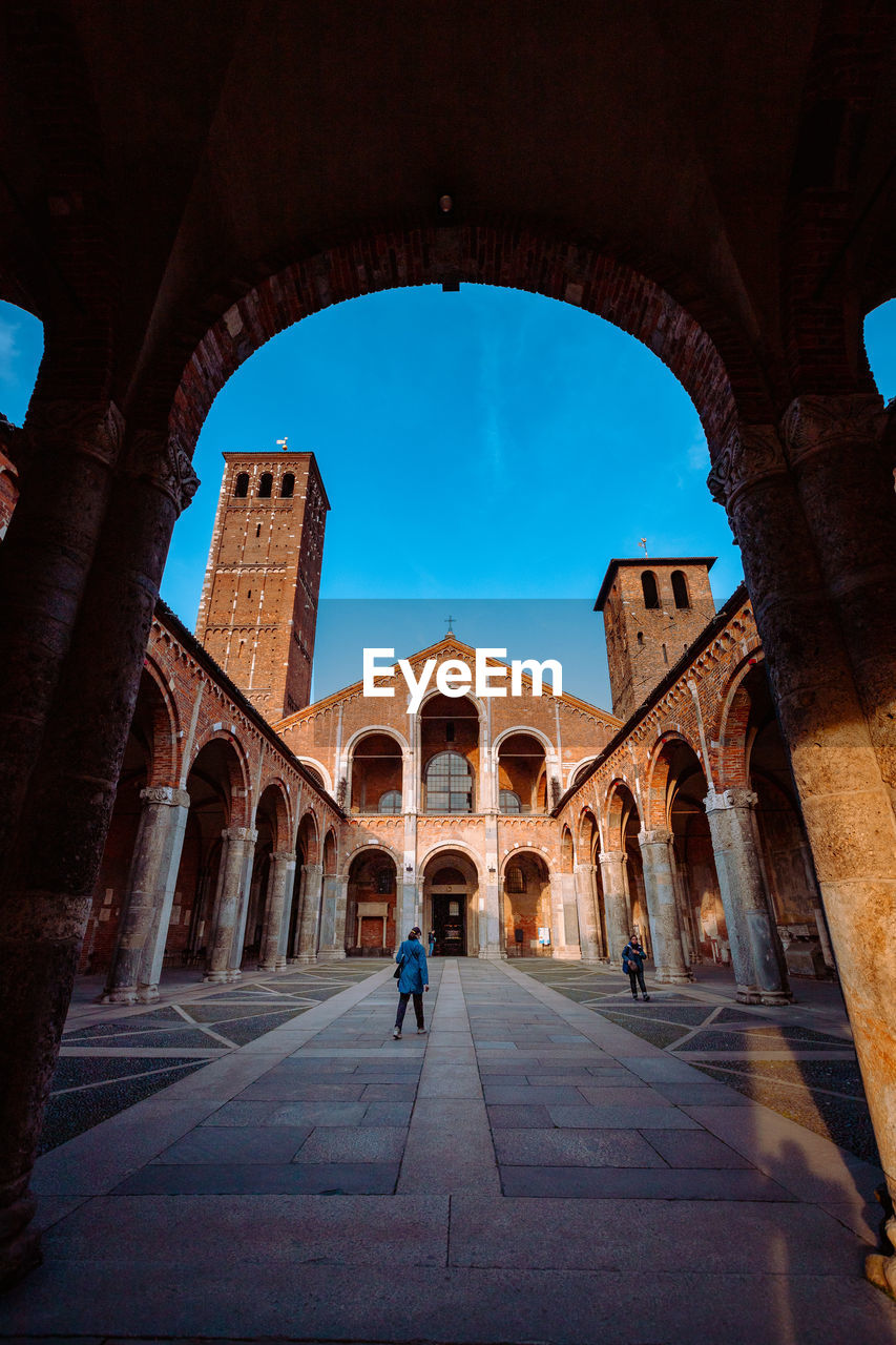 Wide view of the basilica of sant'ambrogio with arcade and person walking