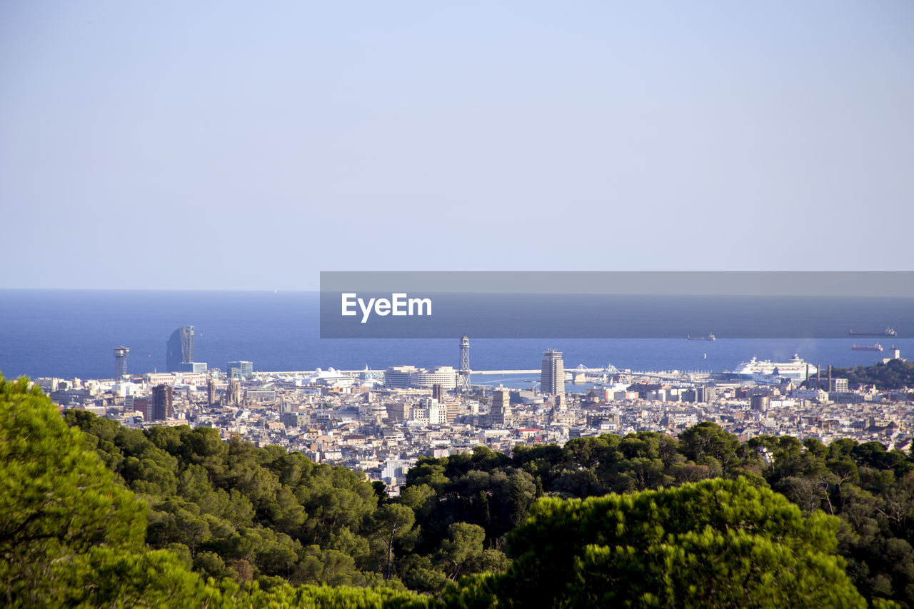 High angle view of cityscape by sea against clear sky