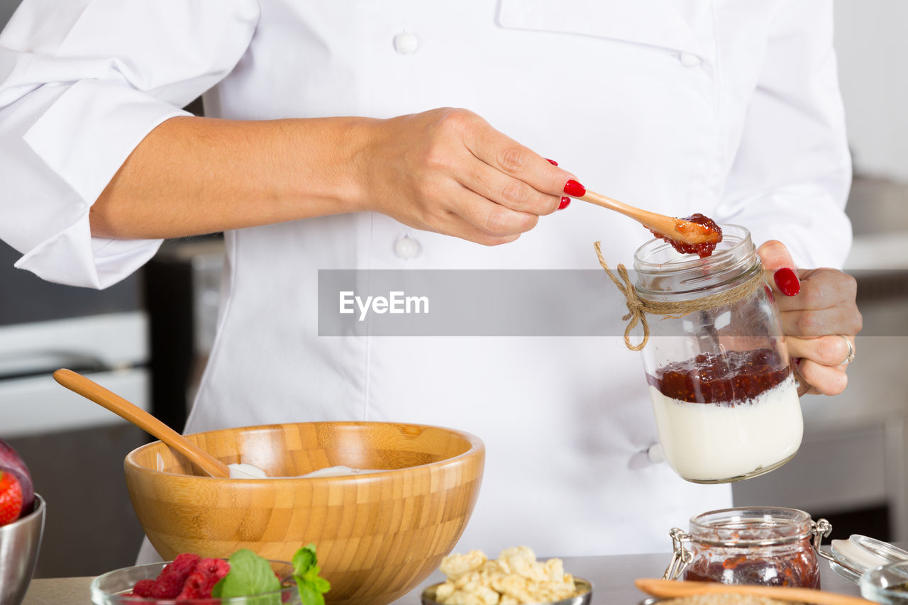 Midsection of chef preparing food in commercial kitchen