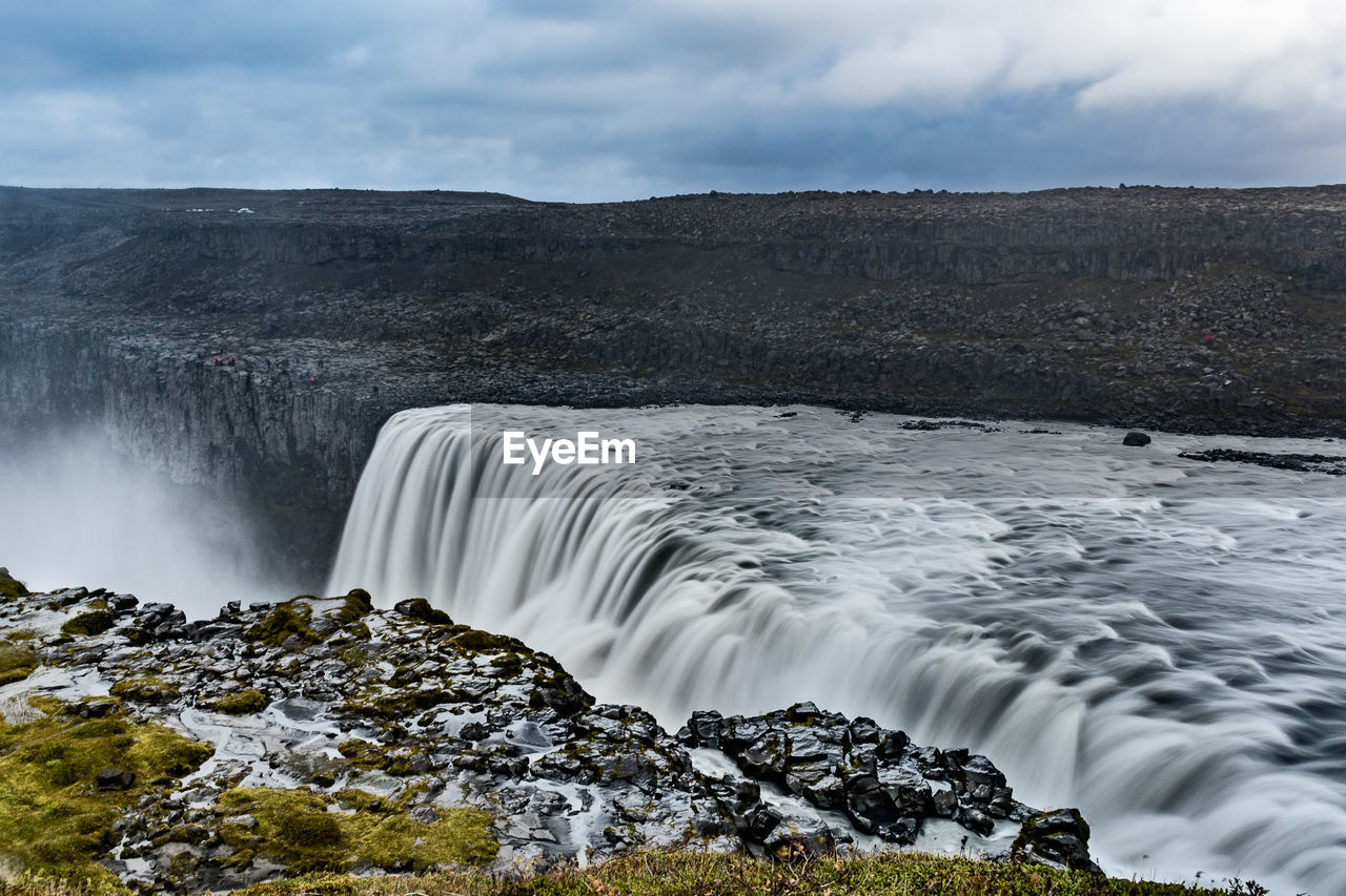 Scenic view of waterfall and landscape against sky