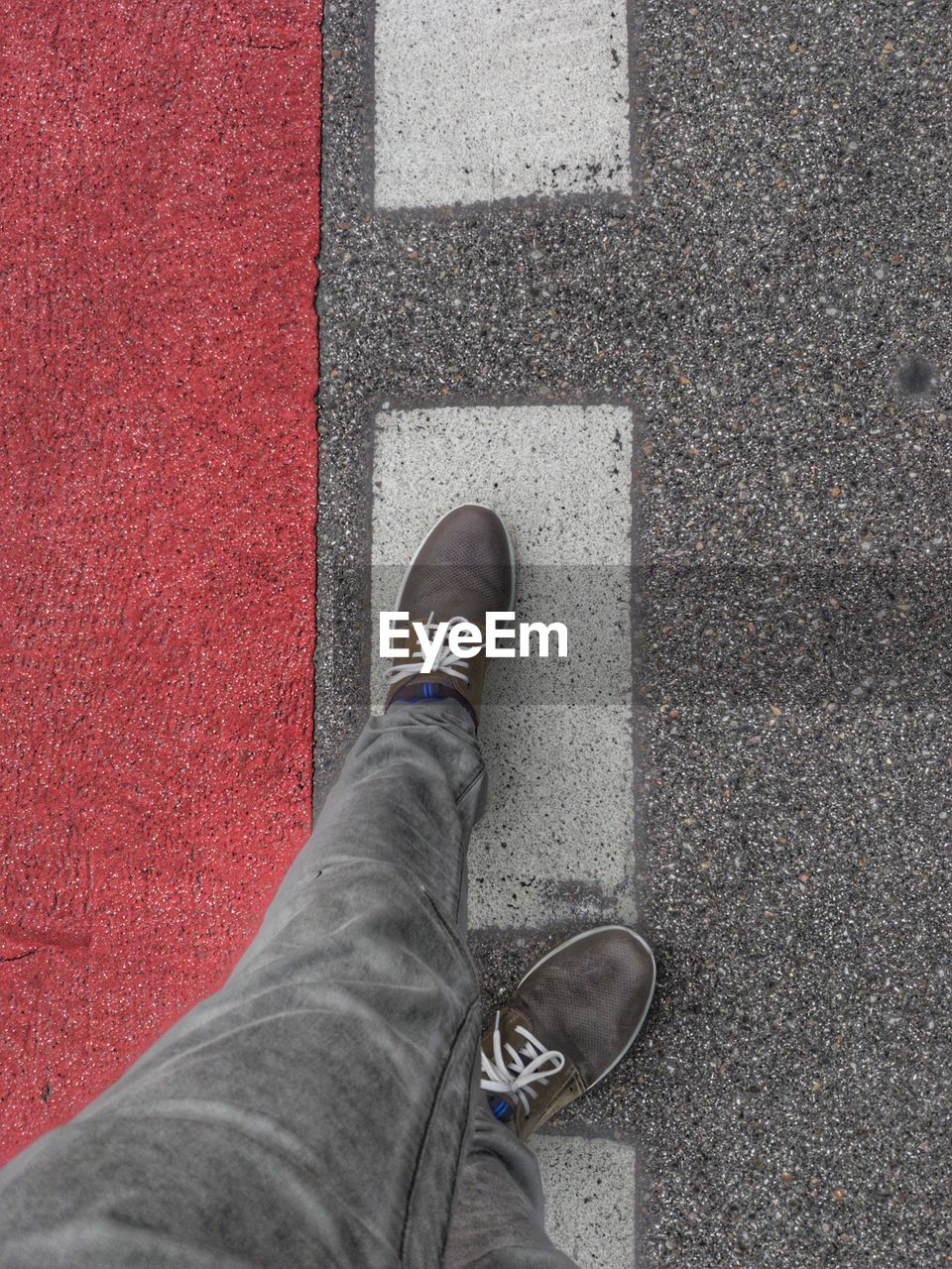 LOW SECTION OF MAN STANDING ON ASPHALT