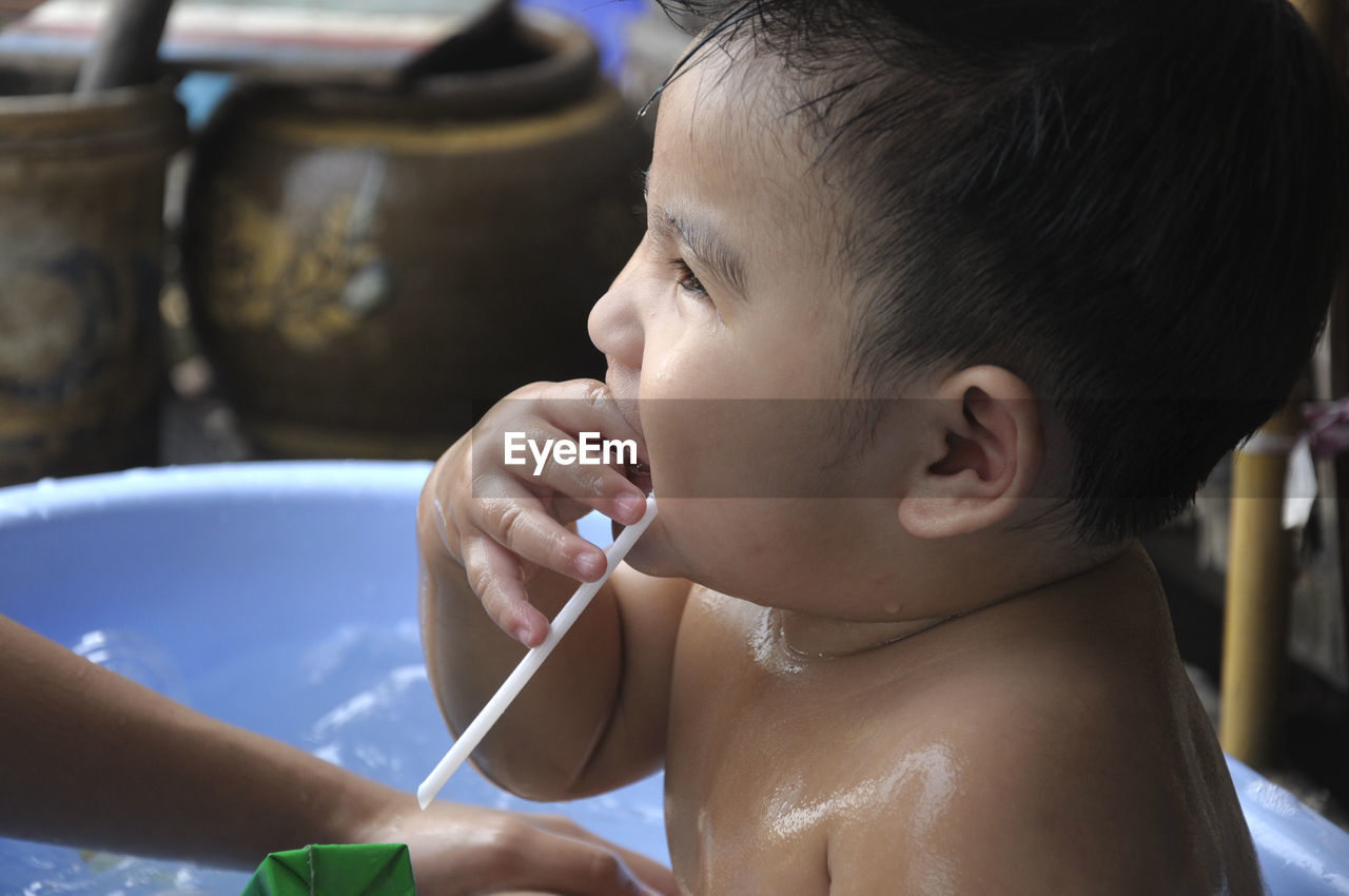 Side view of shirtless baby boy sitting in bathtub