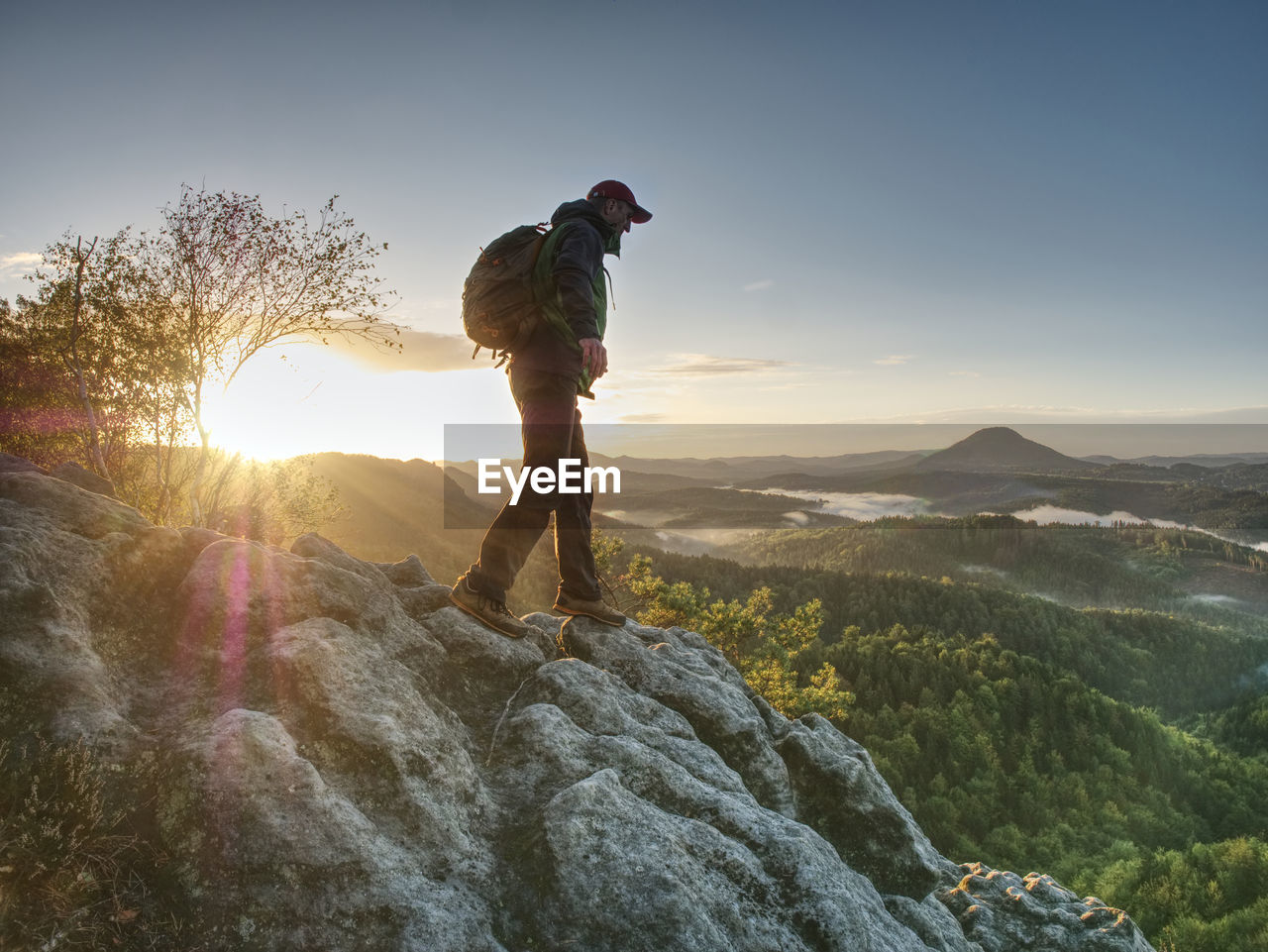 Moment of daybreak. man on rocky trail stop to enjoy view to morning sun, silhouette on the rock