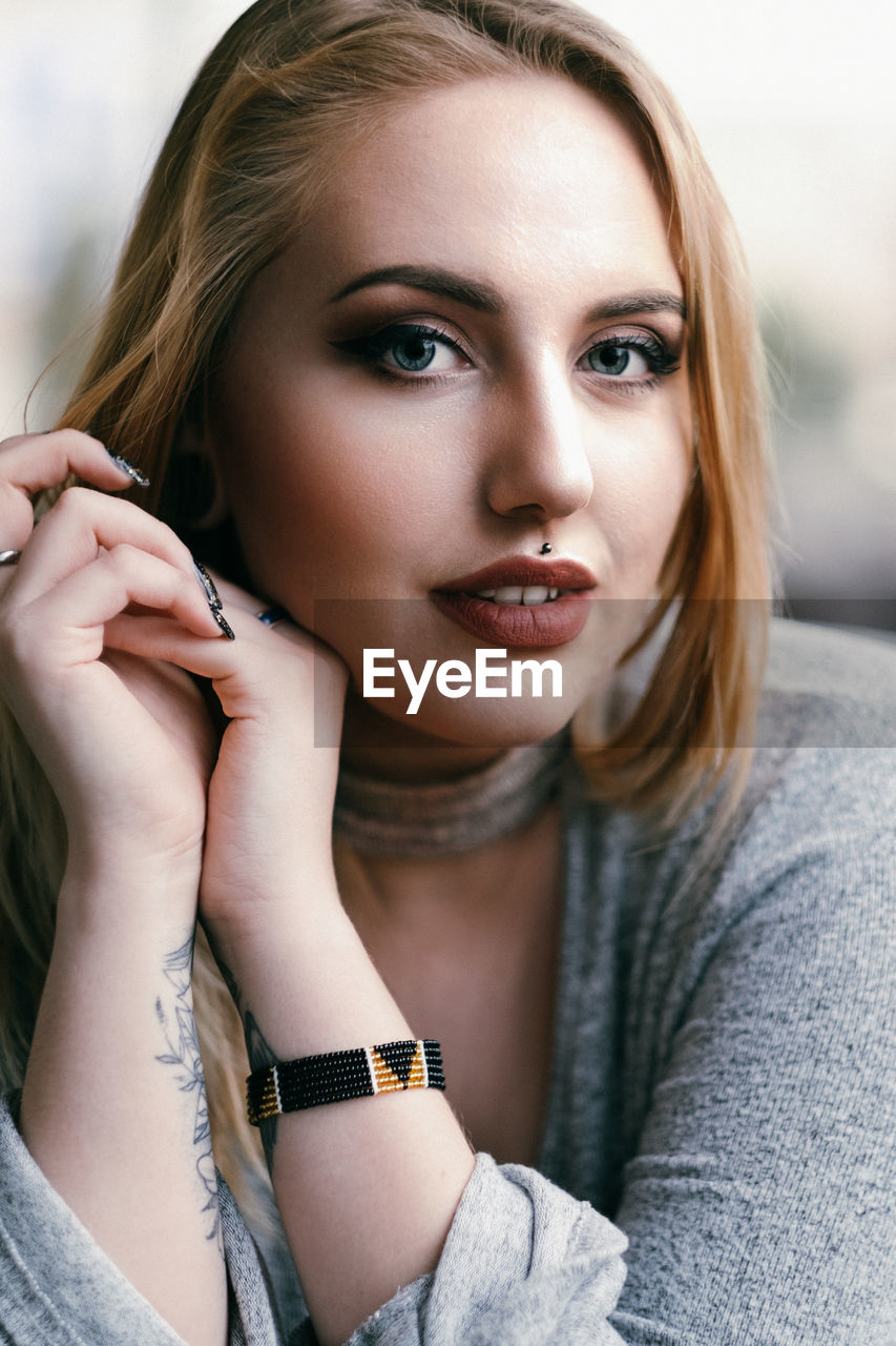 CLOSE-UP OF BEAUTIFUL YOUNG WOMAN SITTING WITH HANDS