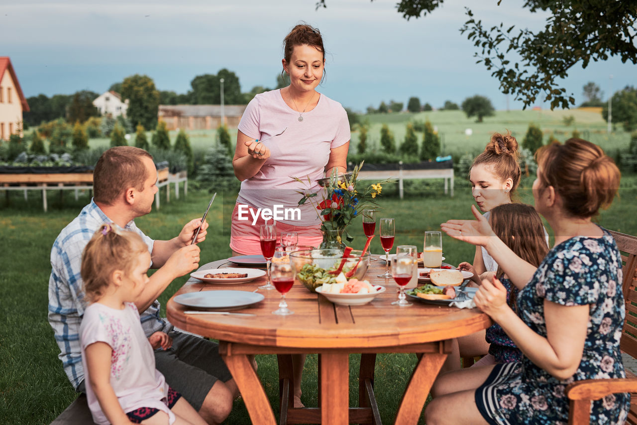 Cheerful family eating food while sitting outdoors