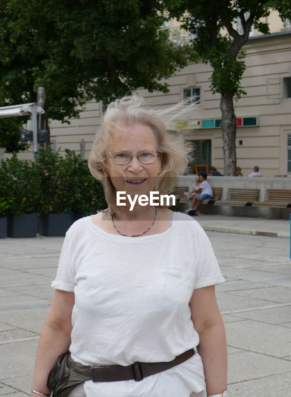 Portrait of smiling mature woman standing on footpath