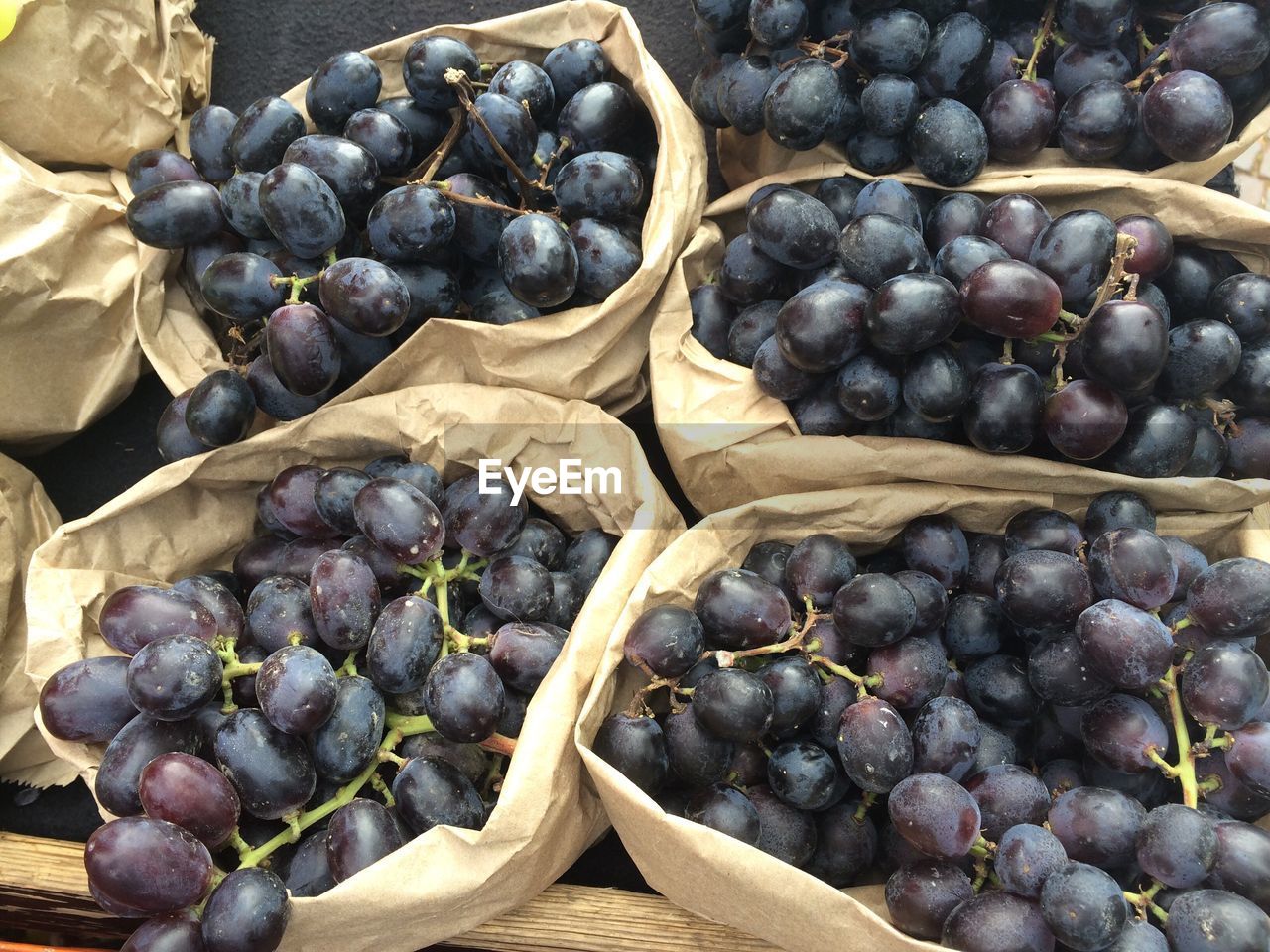 High angle view of red grapes in paper bags for sale at market stall