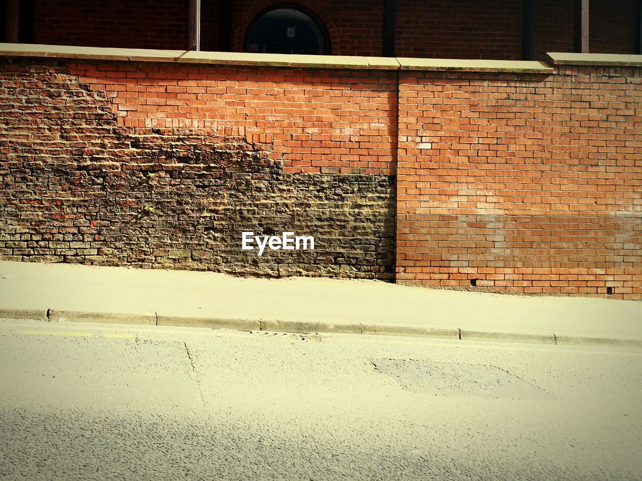 SHADOW OF BRICK WALL ON SIDEWALK