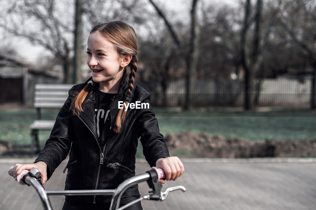 Smiling girl with bicycle at park