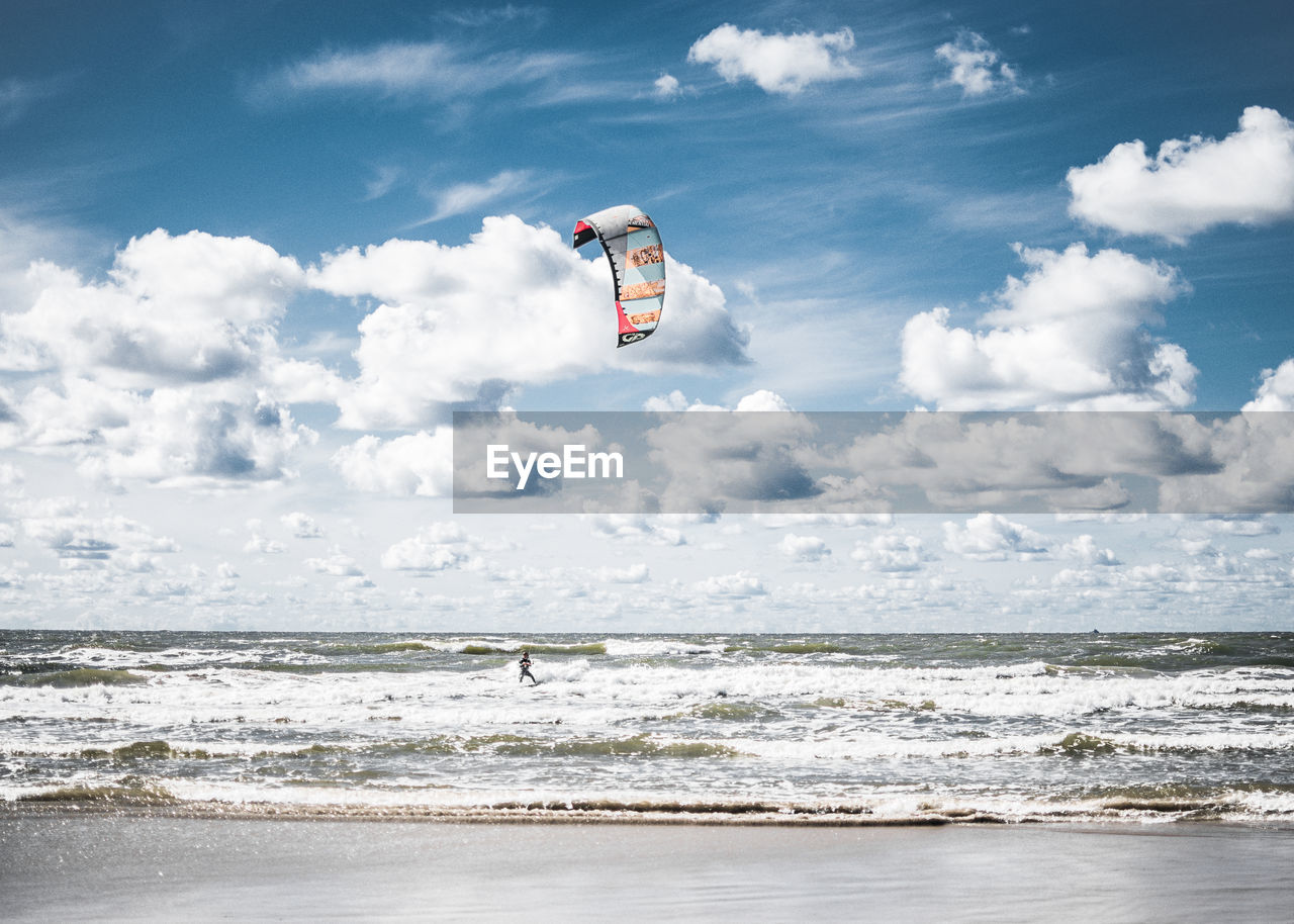 Scenic view of sea against sky with person kiteboarding