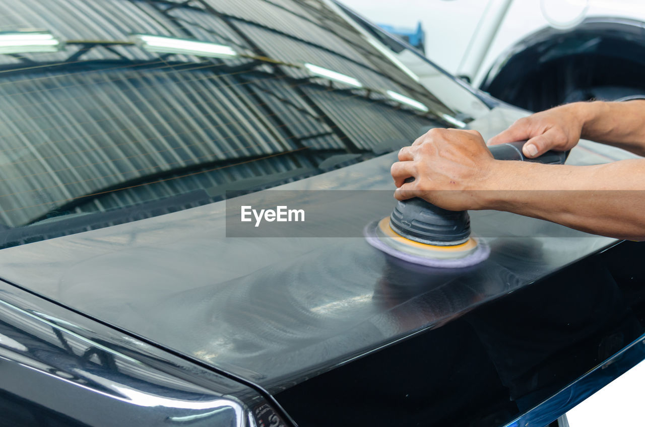 MIDSECTION OF MAN WORKING ON CAR