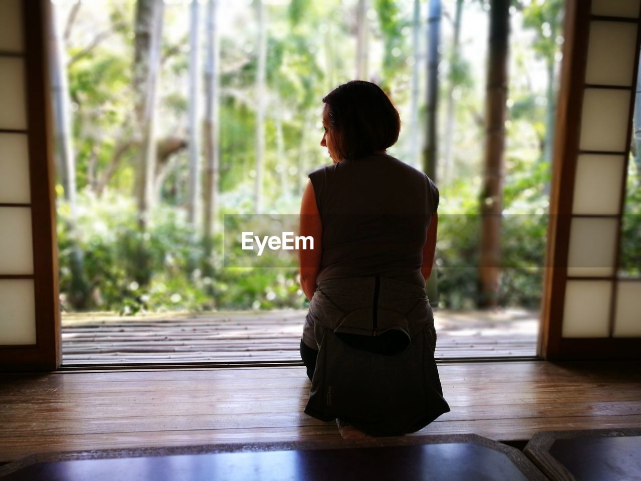 Rear view of woman sitting at doorway