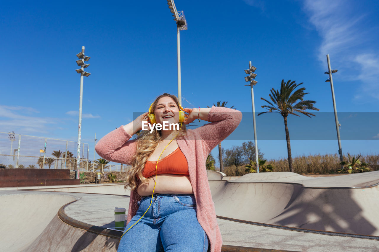 Young woman sitting in skateboard park