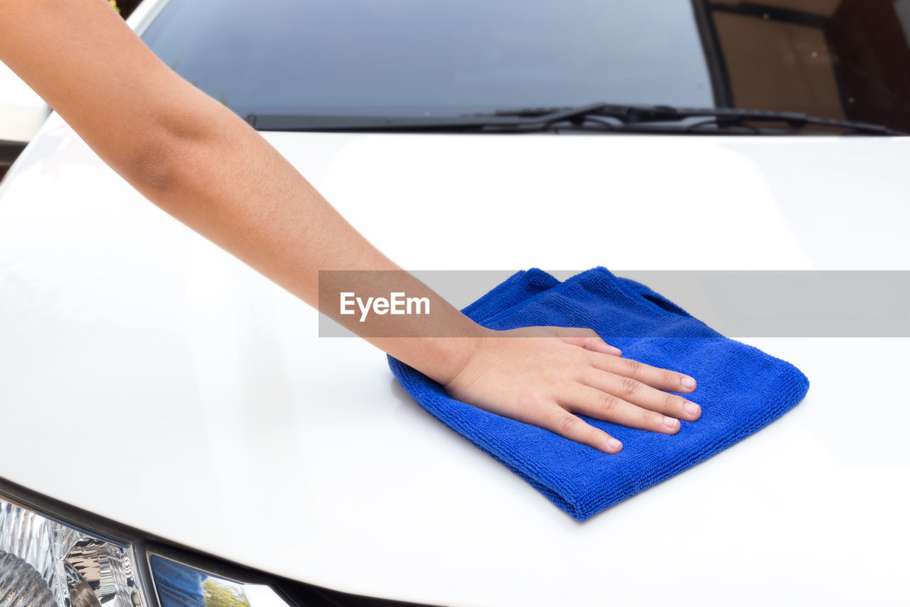 Close-up of woman hand cleaning car hood