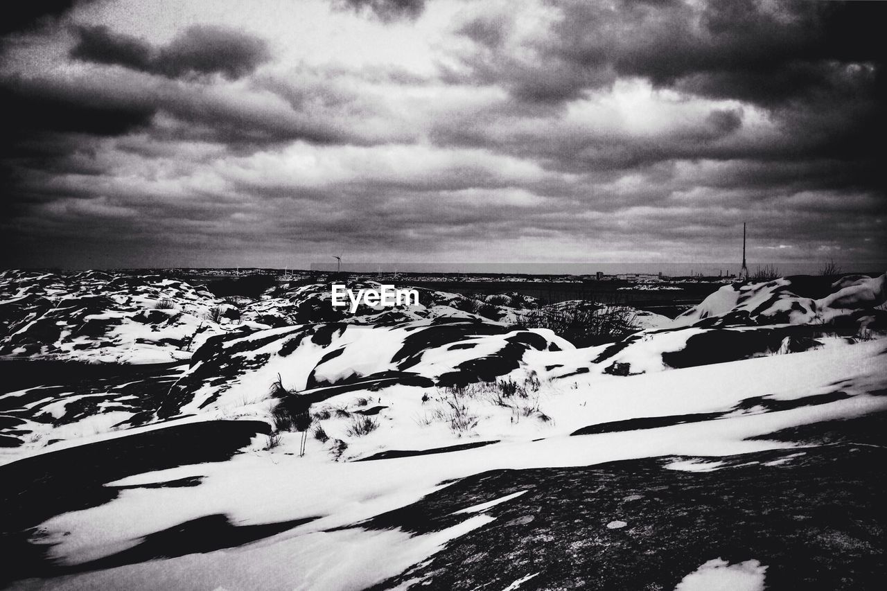 SNOW COVERED LANDSCAPE AGAINST CLOUDY SKY