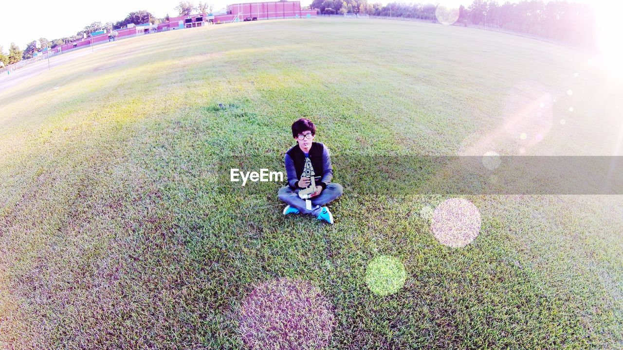 High angle view of teenage boy sitting on lawn